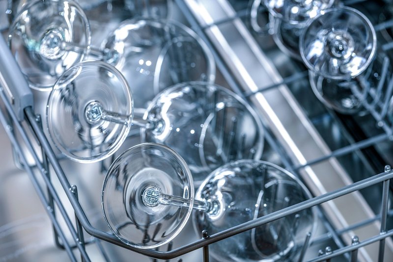 Person cleaning the filter of a built-in dishwasher in a modern kitchen