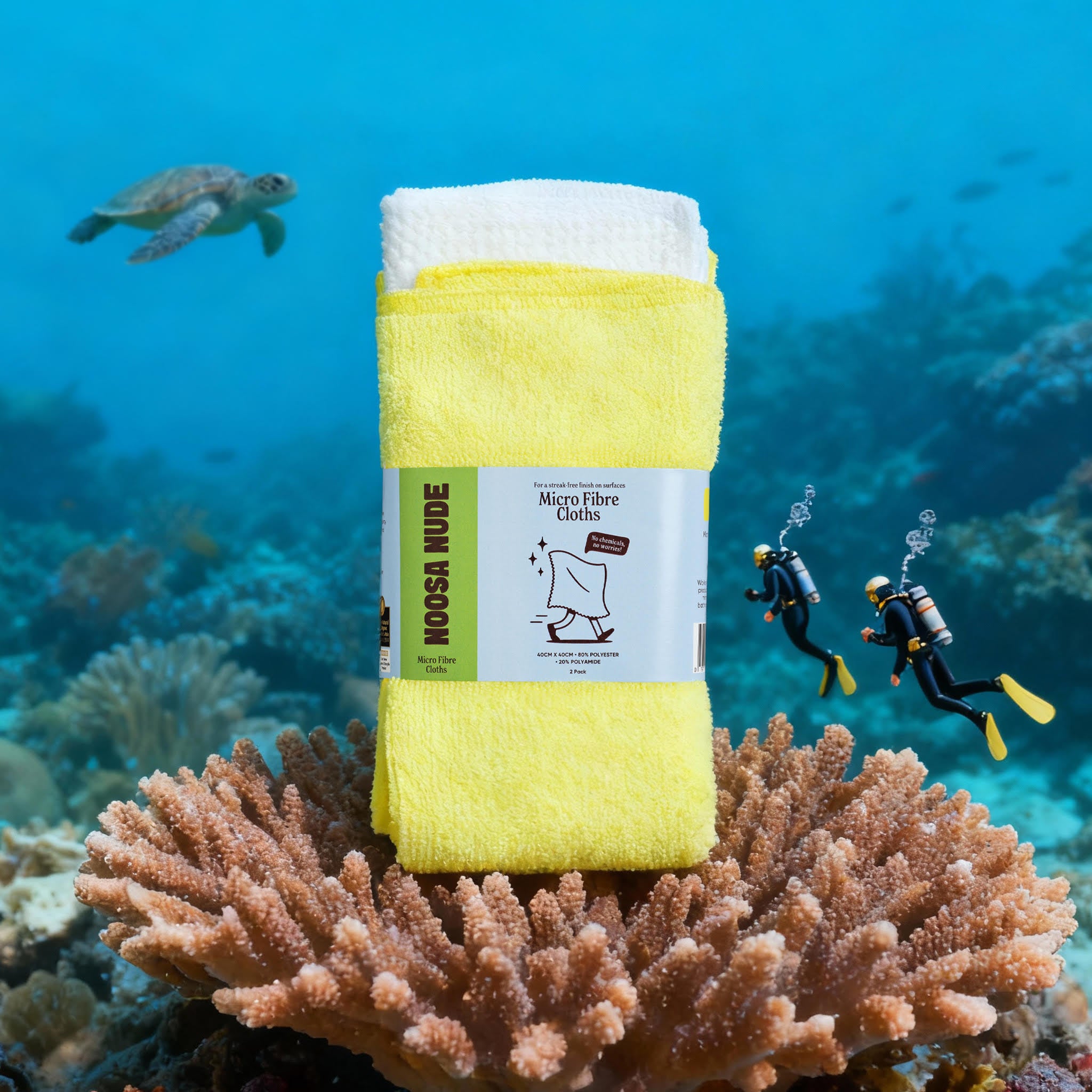 Yellow microfiber cloth on a coral with scuba divers and a turtle in the background